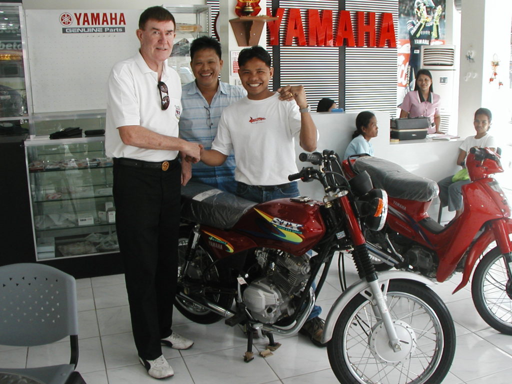 Former boxer Alvin Felisilda, right, poses with his new motorcycle which will be converted to a passenger tricycle, and will allow him to earn a living after a life threatening ring injury ended his career. 